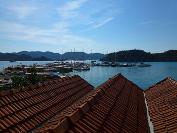 Sailboats moored in harbor against sky