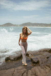 Full length of young woman standing at beach