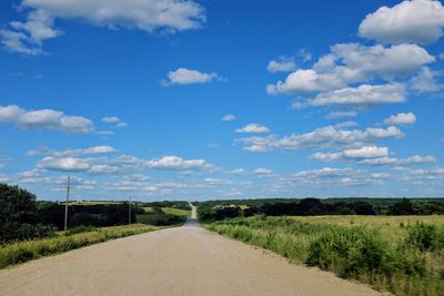 Road by landscape against blue sky