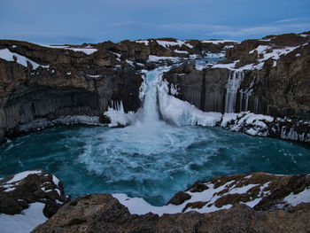 Scenic view of waterfall against sky during winter