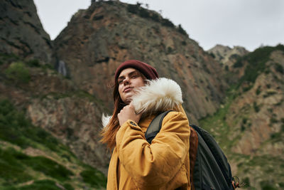 Young woman standing against mountain