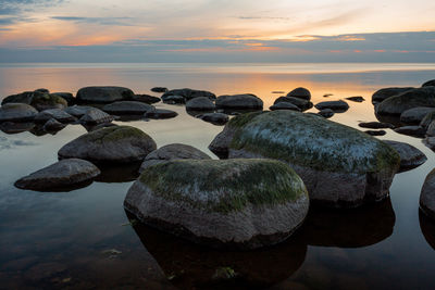 Rocks on beach against sky during sunset