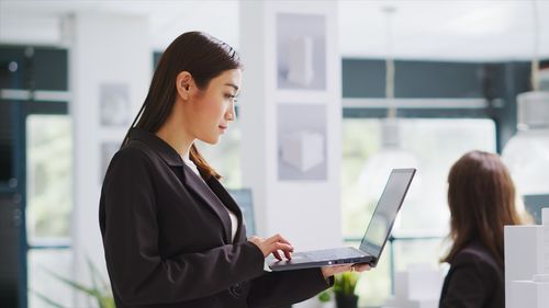 Side view of young businesswoman using laptop at office