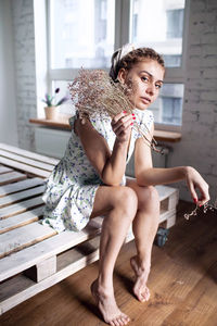 Portrait of young woman sitting on hardwood floor at home