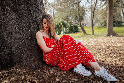 Woman leaning on tree trunk on land 