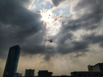 Low angle view of silhouette buildings against cloudy sky