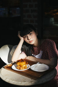 Portrait of young woman sitting on table