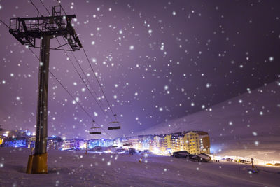 Illuminated street lights against sky at night