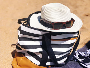 Close-up of sunglasses and hat on bag at beach