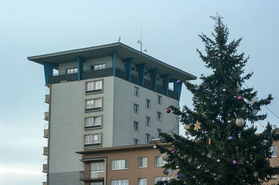 Low angle view of tree by building against sky