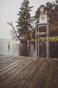 Wooden post by lake against sky