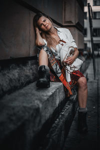 Young woman sitting on wall