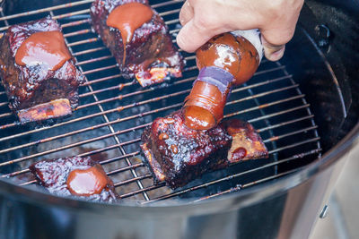 Close-up of person preparing food on barbecue grill