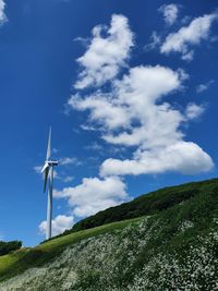 Low angle view of wind turbines against sky