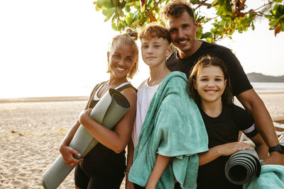 Portrait of smiling children with parents standing at beach during sunset