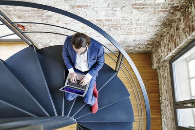 Businessman using laptop on spiral staircase