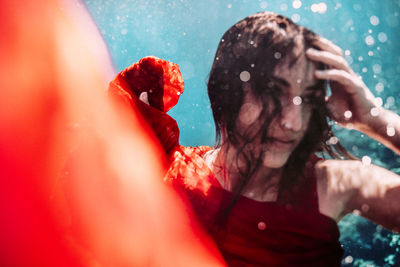 Portrait of woman with red rose in water