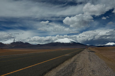 Scenic view of road by mountains against sky