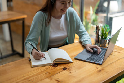 Young woman using laptop while sitting on table