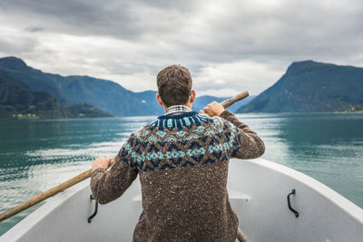 Rear view of man looking at sea against mountain