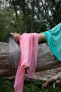 Midsection of woman with pink umbrella on wood in forest