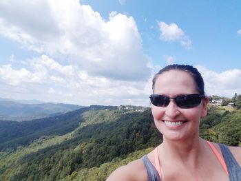 Smiling woman wearing sunglasses against sky