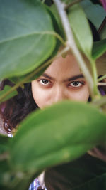 Close-up portrait of young woman with green leaves