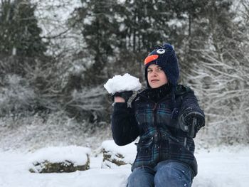 Portrait of teenage boy throwing snowball on field