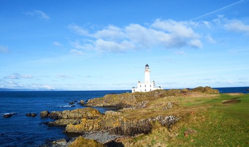 Lighthouse by sea against sky