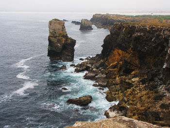 Rock formation on sea shore against sky