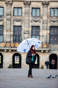 Full length of woman standing on street in rain