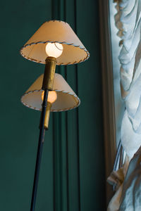 Close-up of illuminated lamp against wall at home