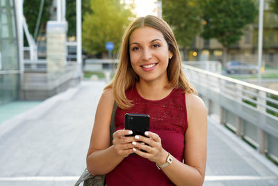 Portrait of smiling young woman using mobile phone