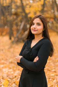 Portrait of young woman standing against trees