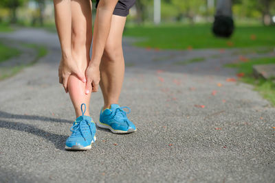 Low section of woman suffering from pain on road