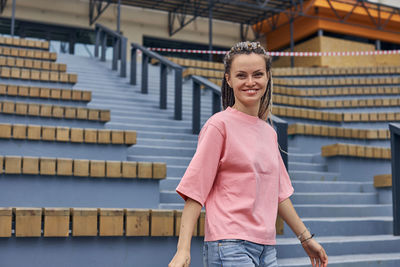 Portrait of smiling woman standing against staircase