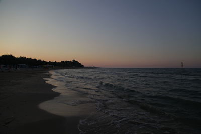 Scenic view of beach against clear sky during sunset