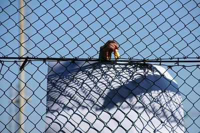 Person holding clothespin with paper on chainlink fence