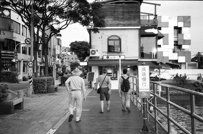 Rear view of people walking on street in city