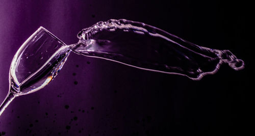 Close-up of water splashing glass against black background