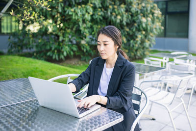 Asian confident business woman working with laptop outdoor, focused