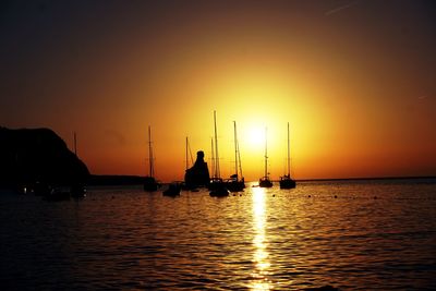 Silhouette sailboats in sea against sky during sunset
