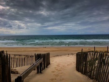 Scenic view of beach against cloudy sky