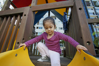 Low angle view of girl playing on slide at playground