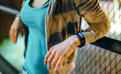 Unrecognizable female wearing digital wrist band on her hand with heart rate monitor on the screen