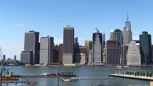 Modern buildings by river against sky in city