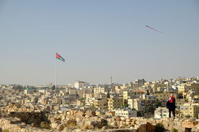 Flag flying over buildings in city against clear sky