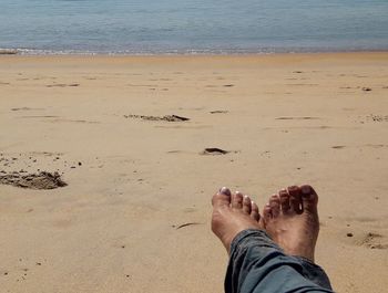 Low section of man standing on beach