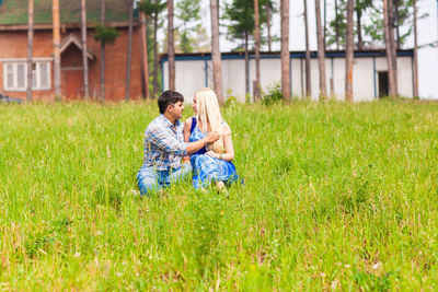 Full length of couple sitting on field