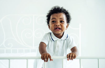 Cute crying boy sitting on bed at home